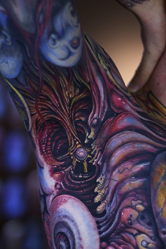 Existem muitos tatuadores especializados em tatuagens biomecânicas e o Dietz Tattoo é um dos melhores quando se trata desse assunto. Seu trabalho se destaca do que vejo por ai por culpa do brilho das suas cores, suas formas surrealistas que mais lembram músculos humanos sendo removidos do seu contexto e depois derretidos como se não fossem nada. É interessante ver um tatuador nesse estilo seguindo um visual, ainda que inspirado por Giger, sendo diferente daquele clichê que vemos todos os dias.