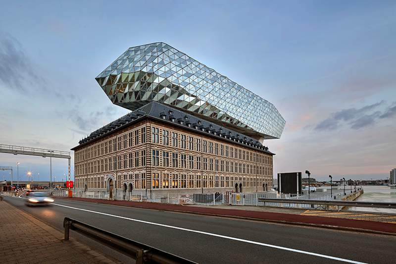 O escritório de arquitetura de Zaha Hadid acabou de inaugurar o novo Port House de Antuérpia, na Bélgica. Essa nova construção usa da estrutura base de uma antiga sede dos bombeiros na zona portuária da cidade e acabou transformando o edifício no centro para os mais de 500 funcionários que trabalhavam em prédios separados pela cidade. A construção foi feita em forma de uma extensão elevada que parece flutuar sobre o edifício original. Sua fachada é feita de vidro com a intenção de refletir as cores do céu e seu formato é inspirado nos navios que cruzam essa cidade belga todos os dias. 