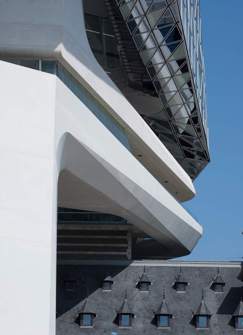 O escritório de arquitetura de Zaha Hadid acabou de inaugurar o novo Port House de Antuérpia, na Bélgica. Essa nova construção usa da estrutura base de uma antiga sede dos bombeiros na zona portuária da cidade e acabou transformando o edifício no centro para os mais de 500 funcionários que trabalhavam em prédios separados pela cidade. A construção foi feita em forma de uma extensão elevada que parece flutuar sobre o edifício original. Sua fachada é feita de vidro com a intenção de refletir as cores do céu e seu formato é inspirado nos navios que cruzam essa cidade belga todos os dias. 