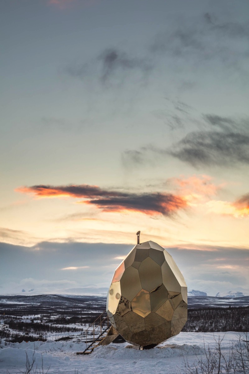 Brilhando na solidão gelada do norte da Suécia você vai encontrar uma estranha construção. Chamada de Solar Egg pelos seus criadores, a dupla conhecida como Bigert & Bergström, essa sauna feita de espelhos dourados é uma obra de arte que brilha no meio de uma paisagem repleta de neve. Essa estrutura é mais que uma sauna e mais do que apenas uma instalação excêntrica. 