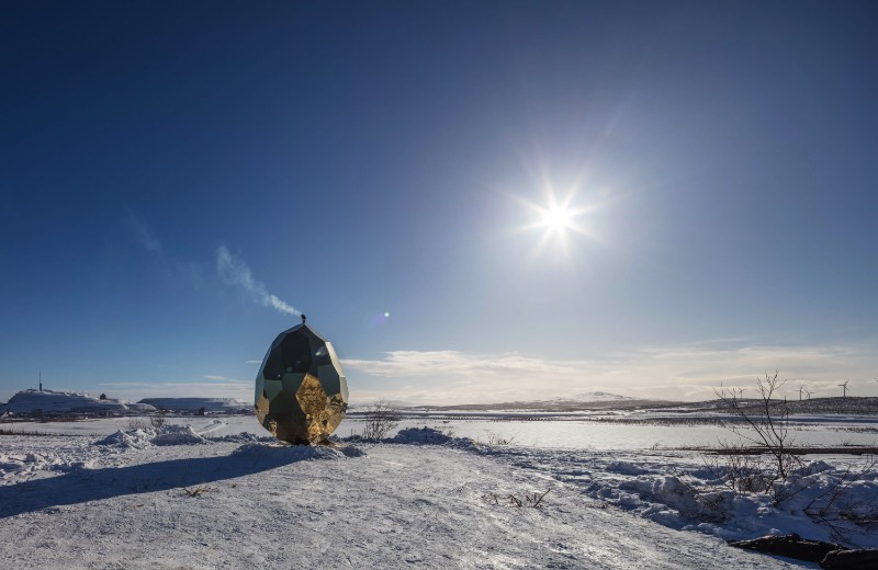 Brilhando na solidão gelada do norte da Suécia você vai encontrar uma estranha construção. Chamada de Solar Egg pelos seus criadores, a dupla conhecida como Bigert & Bergström, essa sauna feita de espelhos dourados é uma obra de arte que brilha no meio de uma paisagem repleta de neve. Essa estrutura é mais que uma sauna e mais do que apenas uma instalação excêntrica. 