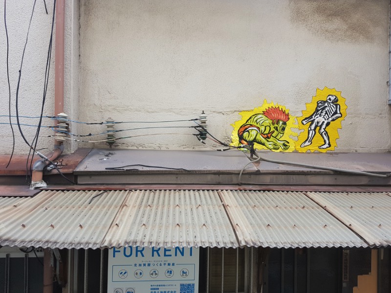 OAKOAK nasceu na cidade de Saint-Etienne, na França. Foi lá que ele começou a colar suas desenhos e produzir sua arte nas ruas. Tudo isso com a ideia de excitar o dia a dia das pessoas quando elas menos esperavam. Um ponto que eu acho interessante no trabalho dele é como ele explora dos pequenos erros da superfície urbana, todos aqueles pequenas rachaduras se tornam seu espaço para arte. É ali que ele adiciona seu ponto de vista, sua visão, seus personagens e suas referências de cultura pop. Dessa forma ele acaba transformando o ambiente urbano em algo mais poético.