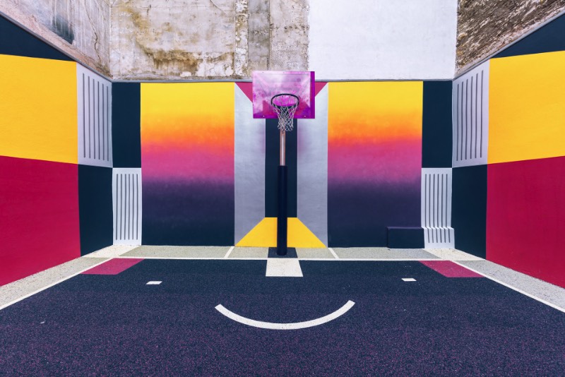 Perdida entre edifícios em Paris, você pode encontrar uma quadra de basquete que é conhecida como Pigalle Basketball Court ou algo similar mas em francês. Lá, o basquete se mistura com a arte e é tudo responsabilidade de Stéphane Ashpool que se juntou a Pigalle, a agência Ill-Studio e ao pessoal da Nike e criaram o visual ultra colorido.