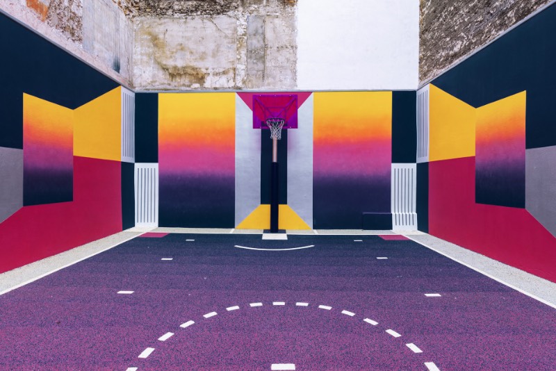 Perdida entre edifícios em Paris, você pode encontrar uma quadra de basquete que é conhecida como Pigalle Basketball Court ou algo similar mas em francês. Lá, o basquete se mistura com a arte e é tudo responsabilidade de Stéphane Ashpool que se juntou a Pigalle, a agência Ill-Studio e ao pessoal da Nike e criaram o visual ultra colorido.