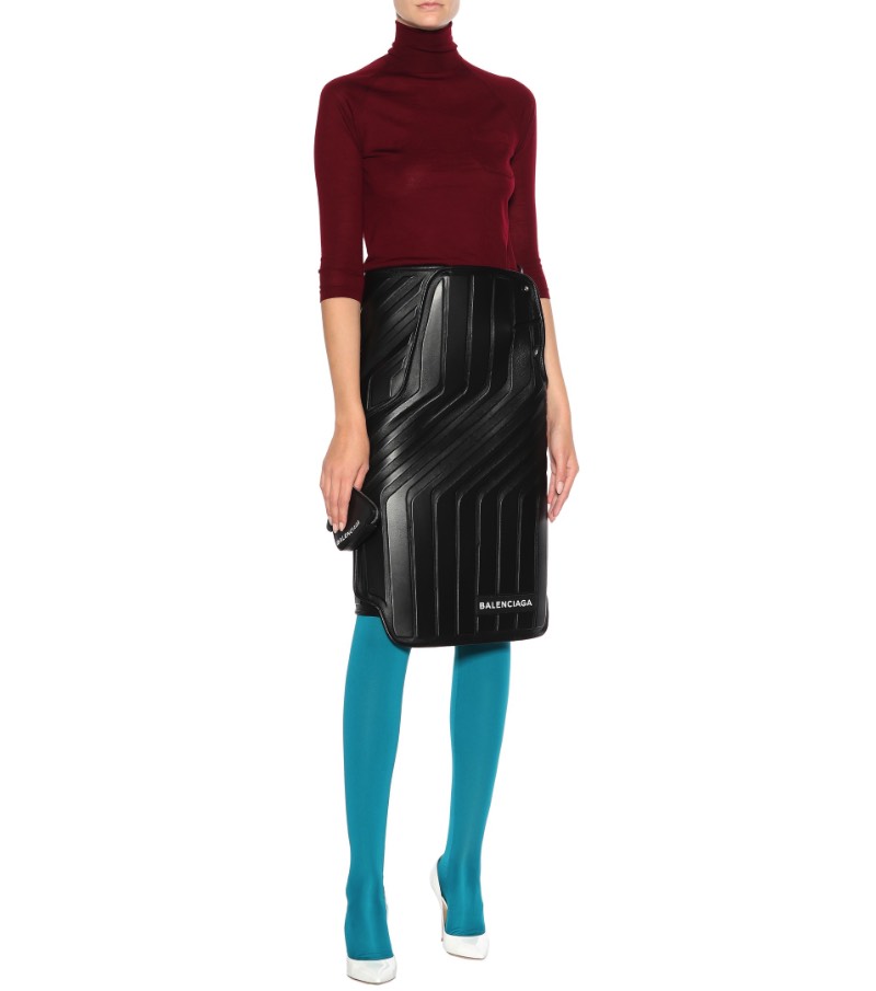 De acordo com o site da Balenciaga, essa saia de couro apareceu para o mundo no Paris Fashion Week e ela transforma o funcional em formal com estilo. Tudo isso porque ela apresenta um padrão interessante feito de couro preto e que é reforçado por neoprene, por uma estética mais utilitária. Além de todo esse visual, essa saia de couro faz parte de uma série chamada logomarca, onde o nome da marca aparece de forma assimétrica e bem proeminente. Mas, o que que foi isso tudo que eu li aqui?