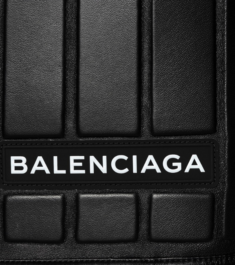 De acordo com o site da Balenciaga, essa saia de couro apareceu para o mundo no Paris Fashion Week e ela transforma o funcional em formal com estilo. Tudo isso porque ela apresenta um padrão interessante feito de couro preto e que é reforçado por neoprene, por uma estética mais utilitária. Além de todo esse visual, essa saia de couro faz parte de uma série chamada logomarca, onde o nome da marca aparece de forma assimétrica e bem proeminente. Mas, o que que foi isso tudo que eu li aqui?