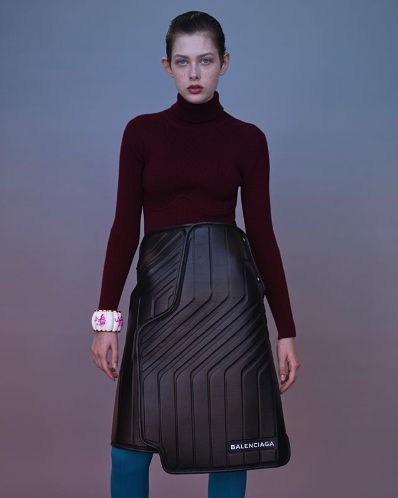 De acordo com o site da Balenciaga, essa saia de couro apareceu para o mundo no Paris Fashion Week e ela transforma o funcional em formal com estilo. Tudo isso porque ela apresenta um padrão interessante feito de couro preto e que é reforçado por neoprene, por uma estética mais utilitária. Além de todo esse visual, essa saia de couro faz parte de uma série chamada logomarca, onde o nome da marca aparece de forma assimétrica e bem proeminente. Mas, o que que foi isso tudo que eu li aqui?