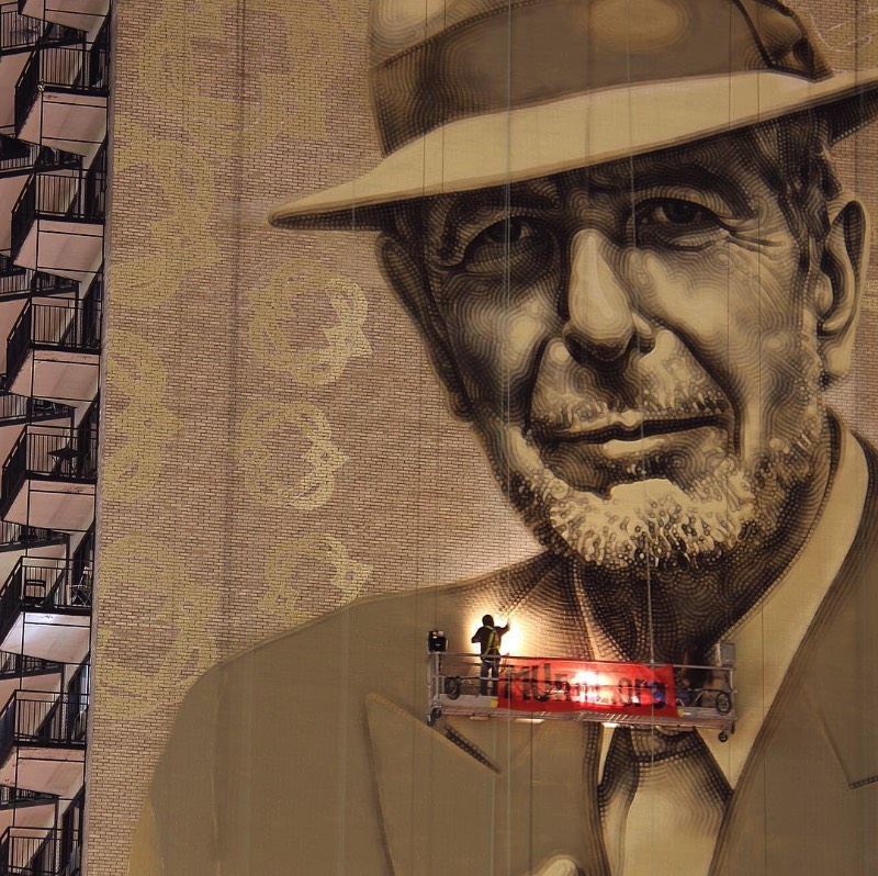 O artista conhecido como El Mac passo um tempo em Montreal, trabalhando para criar um enorme mural para Leonard Cohen em um dos muitos altos prédios da cidade. Esse mural teve a produção e assistência de MU, Gene Penson e um número grande de assistentes que conseguiram colocar em prática o centésimo mural de MU e mais um na coleção de Montreal’s Great Artists. Afinal, o projeto MU quer deixar Montreal mais bonita através de murais e parece que eles estão fazendo isso bem se você olhar as imagens que selecionei para esse artigo.