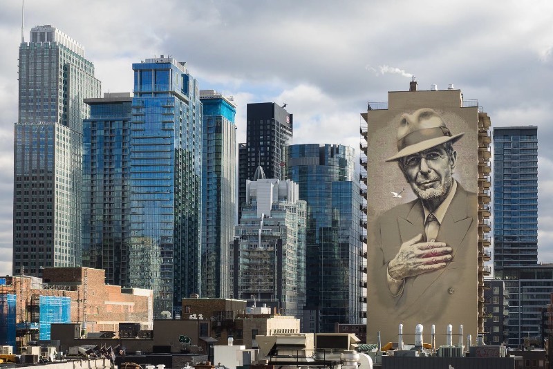 O artista conhecido como El Mac passo um tempo em Montreal, trabalhando para criar um enorme mural para Leonard Cohen em um dos muitos altos prédios da cidade. Esse mural teve a produção e assistência de MU, Gene Penson e um número grande de assistentes que conseguiram colocar em prática o centésimo mural de MU e mais um na coleção de Montreal’s Great Artists. Afinal, o projeto MU quer deixar Montreal mais bonita através de murais e parece que eles estão fazendo isso bem se você olhar as imagens que selecionei para esse artigo.