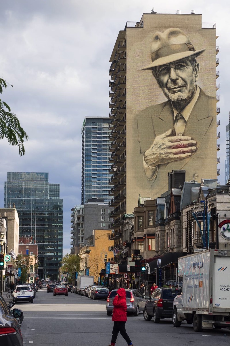O artista conhecido como El Mac passo um tempo em Montreal, trabalhando para criar um enorme mural para Leonard Cohen em um dos muitos altos prédios da cidade. Esse mural teve a produção e assistência de MU, Gene Penson e um número grande de assistentes que conseguiram colocar em prática o centésimo mural de MU e mais um na coleção de Montreal’s Great Artists. Afinal, o projeto MU quer deixar Montreal mais bonita através de murais e parece que eles estão fazendo isso bem se você olhar as imagens que selecionei para esse artigo.