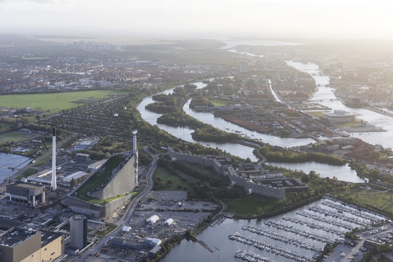 Copenhagen, a capital da Dinamarca, prometeu a seus cidadãos que seria a primeira cidade a neutralizar o carbono. Tudo isso precisa ser feito até 2025 e um dos projetos chave da cidade para colocar isso em prático é conhecido como CopenHill, criação dos designers do Bjarke Ingels Group. 