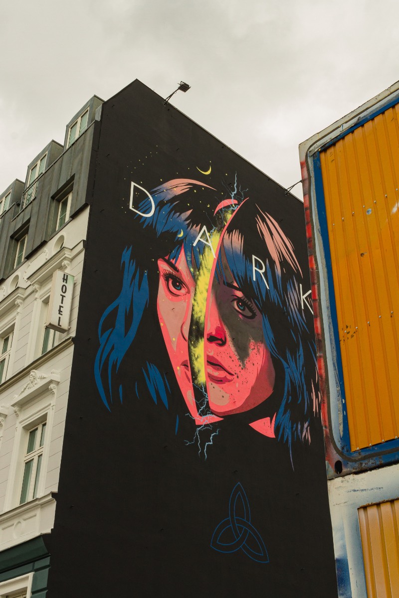 O segundo mural que fui ver fica do lado da famosa East Side Gallery e foi feito por Dale Lendl Romero. A imagem aqui mostra uma Martha dividida no meio, uma clara analogia a separação de mundos que acontece no final da segunda temporada. Visualmente falando, esse é um dos meus trabalhos favoritos já que a linha de ilustração é bem legal, as cores ficaram ótimas e eu usaria uma camiseta com esse desenho sem muitos problemas.