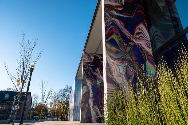 Anne Vieux é uma artista, baseada em Nova Iorque, que recentemente contribui para um projeto de intervenção urbana no centro de Bentonville, no estado americano do Arkansas. Essa instalação de arte de rua consiste em um mural quase holográfico que foi concebido pela artista de forma imersiva já que integra o projeto arquitetônico do prédio ao redor e suas paredes.