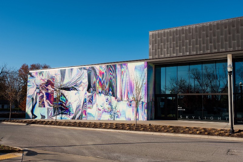 Anne Vieux é uma artista, baseada em Nova Iorque, que recentemente contribui para um projeto de intervenção urbana no centro de Bentonville, no estado americano do Arkansas. Essa instalação de arte de rua consiste em um mural quase holográfico que foi concebido pela artista de forma imersiva já que integra o projeto arquitetônico do prédio ao redor e suas paredes.