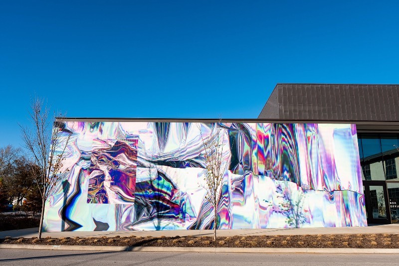 Anne Vieux é uma artista, baseada em Nova Iorque, que recentemente contribui para um projeto de intervenção urbana no centro de Bentonville, no estado americano do Arkansas. Essa instalação de arte de rua consiste em um mural quase holográfico que foi concebido pela artista de forma imersiva já que integra o projeto arquitetônico do prédio ao redor e suas paredes.