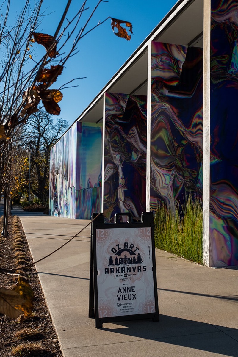 Anne Vieux é uma artista, baseada em Nova Iorque, que recentemente contribui para um projeto de intervenção urbana no centro de Bentonville, no estado americano do Arkansas. Essa instalação de arte de rua consiste em um mural quase holográfico que foi concebido pela artista de forma imersiva já que integra o projeto arquitetônico do prédio ao redor e suas paredes.