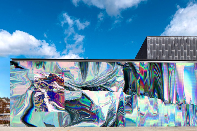 Anne Vieux é uma artista, baseada em Nova Iorque, que recentemente contribui para um projeto de intervenção urbana no centro de Bentonville, no estado americano do Arkansas. Essa instalação de arte de rua consiste em um mural quase holográfico que foi concebido pela artista de forma imersiva já que integra o projeto arquitetônico do prédio ao redor e suas paredes.