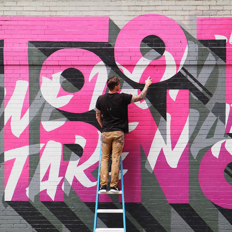 Ben Johnston é um artista cujo portfólio parece ser completamente focado em lettering e tipografia customizada para instalações, murais e arte pública. Aqui, eu resolvi explorar o que ele anda fazendo quando se trata de murais e as imagens que acabei selecionando para esse artigo são, essencialmente, nessa área de trabalho.