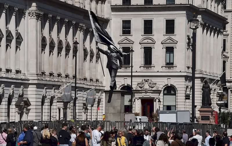 A histórica Waterloo Place, em Londres, é conhecida por seus monumentos a heróis de guerra e à realeza. Mas, no final de abril de 2026, as pessoas que passaram por essa praça foram surpreendidas com uma nova adição à paisagem urbana. Uma estátua do Banksy foi colocada em um pedestal, retratando um homem de terno, cego pela bandeira que carrega, congelado no instante em que parece estar à beira de um precipício.