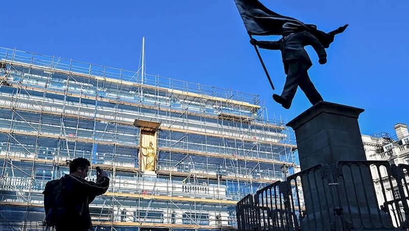 A histórica Waterloo Place, em Londres, é conhecida por seus monumentos a heróis de guerra e à realeza. Mas, no final de abril de 2026, as pessoas que passaram por essa praça foram surpreendidas com uma nova adição à paisagem urbana. Uma estátua do Banksy foi colocada em um pedestal, retratando um homem de terno, cego pela bandeira que carrega, congelado no instante em que parece estar à beira de um precipício.