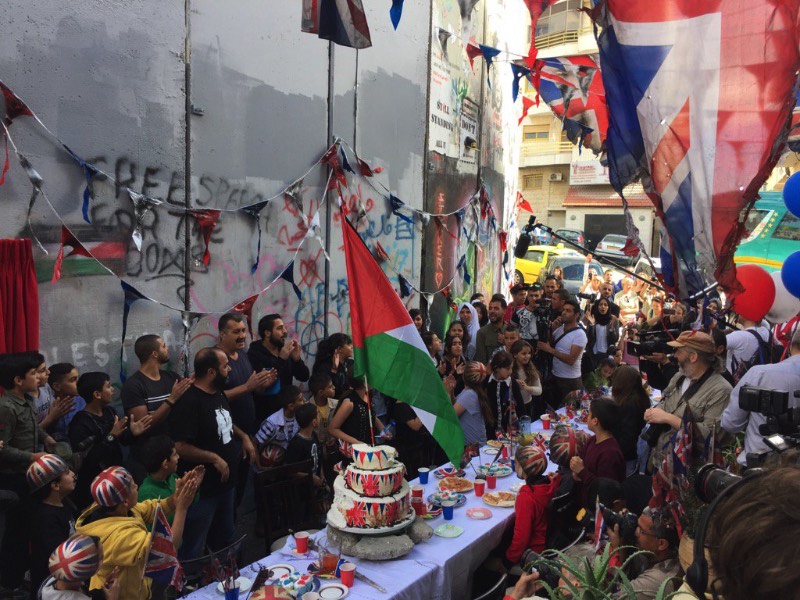 O dia 2 de novembro é um dia bem importante para os moradores da Palestina. Afinal, foi nesse dia, em 1917, que o governo Britânico divulgou um anunciado apoiado a criação de um estado para o povo judeu que acabou levando a criação de Israel. No centenário desse dia, o artista Banksy resolveu fazer uma festa pedindo desculpas pelo papel do Reino Unido em tudo que aconteceu depois da assinatura do Tratado de Balfour. O evento aconteceu na quarta feira, na frente do famosa Walled Off Hotel na cidade de Bethlehem.