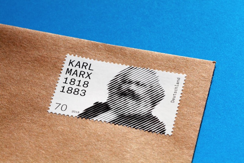 O serviço de correios da Alemanha resolveu lançar um selo celebrando os 200 anos do nascimento de Karl Marx, um dos filósofos mais importantes do país. Esse selo foi criado pelo artista visual Thomas Mayfried que ganhou uma competição aberta criada pelo Ministério Federal das Finanças da Alemanha. O selo tem uma estética abstrata e em preto e branco que foi baseada em uma icônica fotografia de Karl Marx feita em 1875 pelo fotógrafo inglês John Mayall.
