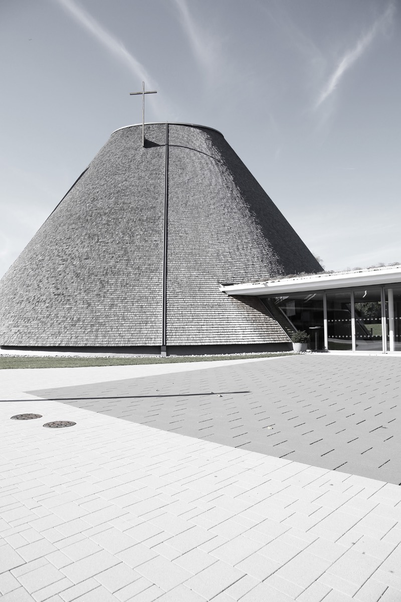 A igreja de São José de Holzkirchen foi concluída em 2016 e tem a assinatura do arquiteto alemão Eberhard Wimmer. Foi ele que projetou a estrutura cônica, feita de anéis horizontais de madeira, aço e coberto por telhas de madeira. Por dentro, o formato da igreja tem o objetivo de conduzir os olhos de seus visitantes para a luz e foi isso que chamou minha atenção nas fotografias que Birgit Schlosser tirou no local.