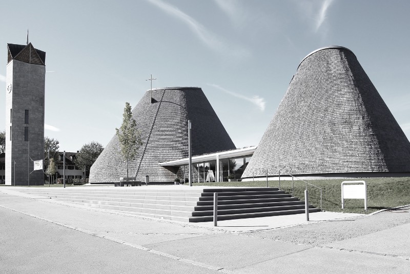 A igreja de São José de Holzkirchen foi concluída em 2016 e tem a assinatura do arquiteto alemão Eberhard Wimmer. Foi ele que projetou a estrutura cônica, feita de anéis horizontais de madeira, aço e coberto por telhas de madeira. Por dentro, o formato da igreja tem o objetivo de conduzir os olhos de seus visitantes para a luz e foi isso que chamou minha atenção nas fotografias que Birgit Schlosser tirou no local.